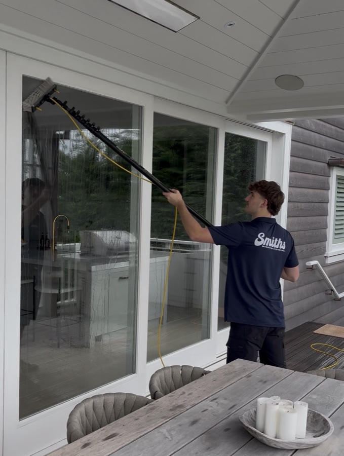 Technician using a water-fed pole to clean exterior windows