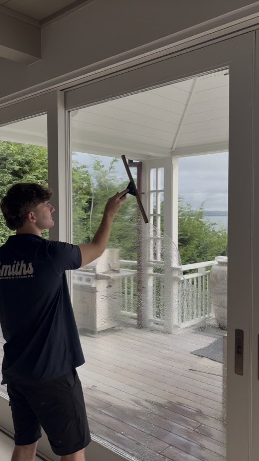 Technician cleaning an interior window with a squeegee